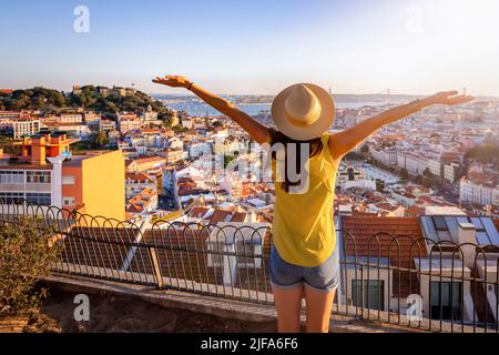 Una donna turistica felice si affaccia sul colorato centro storico di Alfama di Lisbona Foto Stock