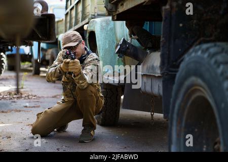 Giovane in corso di formazione tattica. Campo di ripresa all'aperto. Appaltatore militare privato al corso di formazione tattica. Tattiche difensive corso sparatutto, uomo con una pistola in uniforme militare. Foto Stock