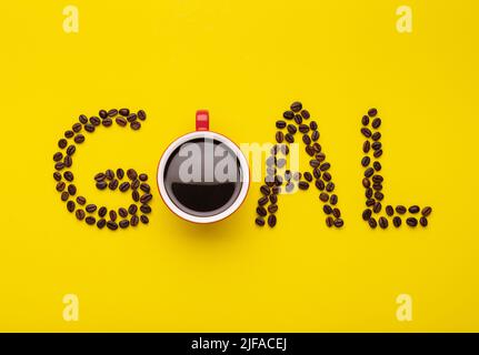 Vista dall'alto di Americano in tazza rossa e chicchi di caffè incantano il GOL parola su sfondo giallo Foto Stock