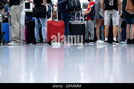 Monaco di Baviera, Germania. 01st luglio 2022. I passeggeri si trovano con i bagagli presso un banco check-in presso l'aeroporto di Monaco. Molti passeggeri sono ancora in attesa dei bagagli una settimana dopo la sosta all'aeroporto di Monaco. Credit: Sven Hoppe/dpa/Alamy Live News Foto Stock