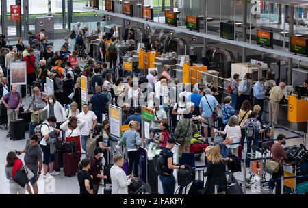 Monaco di Baviera, Germania. 01st luglio 2022. I passeggeri si trovano con i bagagli presso i banchi check-in dell'aeroporto di Monaco. Molti passeggeri sono ancora in attesa dei bagagli una settimana dopo la sosta all'aeroporto di Monaco. Credit: Sven Hoppe/dpa/Alamy Live News Foto Stock