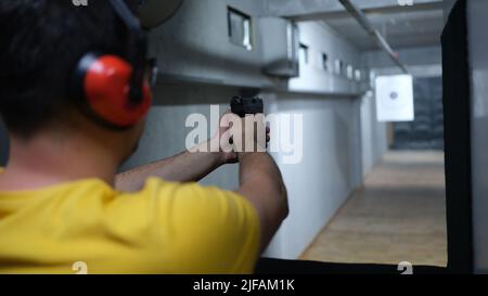 Sparatutto spara dalla pistola in primo piano del poligono di tiro Foto Stock