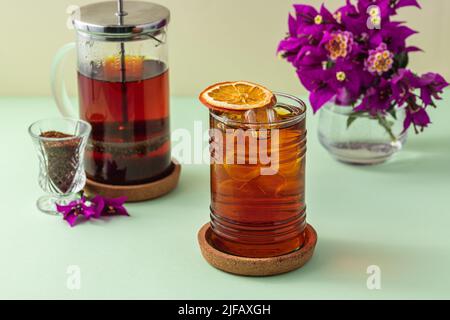 Tè di frutta rossa ghiacciata appena fatto su un tavolo verde Foto Stock