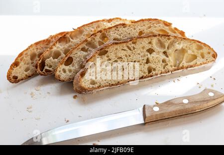 Pane bianco a fette e un coltello. Quattro fette di pane affettato. Foto Stock