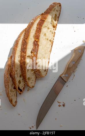 Pane bianco a fette e un coltello. Quattro fette di pane affettato. Vista dall'alto Foto Stock