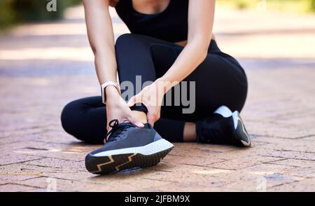 Primo piano di una donna di razza mista che tiene la sua caviglia irritata mentre si esercita all'aperto. Atleta femminile che soffre di lesioni dolorose al piede da fratture Foto Stock