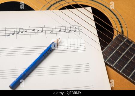 Scena di registrazione musicale con chitarra, spartiti musicali e matita su tavolo di legno Foto Stock