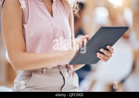 Primo piano di una donna d'affari che naviga su un tablet digitale in un ufficio. Una sola donna che usa Internet online e scarica applicazioni per Foto Stock
