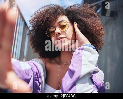 Ritratto di giovane trendy bella donna mista gara con un afro che prende selfie e posa da solo all'esterno. Donna ispanica con capelli ricci Foto Stock