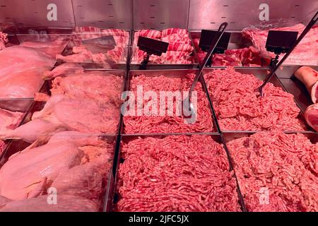 Carne fresca sminuzzata di qualità in frigorifero in vetrina presso il moderno macellaio. Banco di carne. Primo piano. Foto Stock