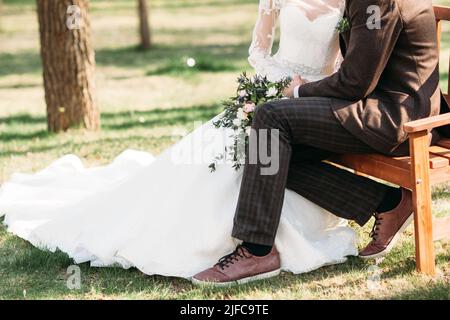 Sposa e lo sposo seduta sul banco in posizione di parcheggio Foto Stock