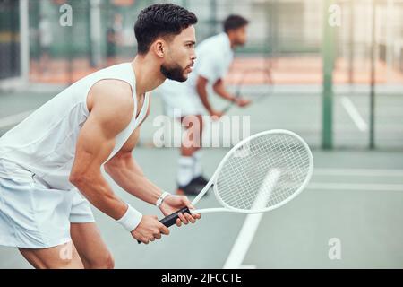 Due giocatori di tennis etnici che tengono racchette e pronti a giocare a gioco di campo. Atleti seri e concentrati insieme in posizione. Giocare a due giocatori competitivi Foto Stock