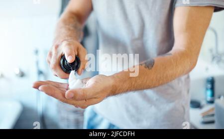 Un uomo sconosciuto che applica la schiuma da barba al viso in un bagno a casa. Un maschio irriconoscibile usando lo shampoo della barba nel suo appartamento Foto Stock