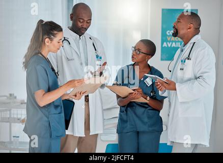 Gruppo di diversi medici che hanno una riunione insieme lavorando in un ospedale. Team di professionisti medici che parlano mentre pianificano la loro giornata di lavoro a un Foto Stock