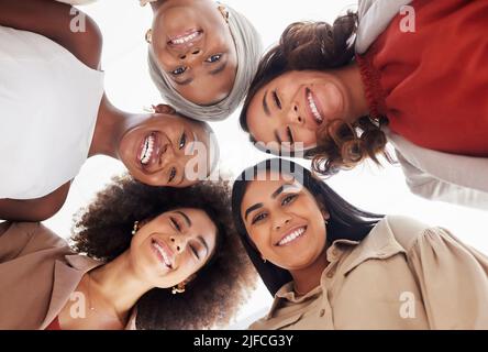 Ritratto ad angolo basso di gruppo diversificato di donne d'affari accoccolato insieme con le teste nel centro. Sorridente gruppo etnico di colleghi professionisti sensazione Foto Stock