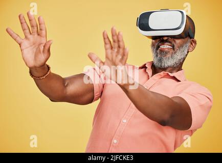 Un uomo afroamericano maturo che utilizza una cuffia per realtà virtuale mentre si trova in studio isolato su uno sfondo giallo. Bell'uomo con un Foto Stock