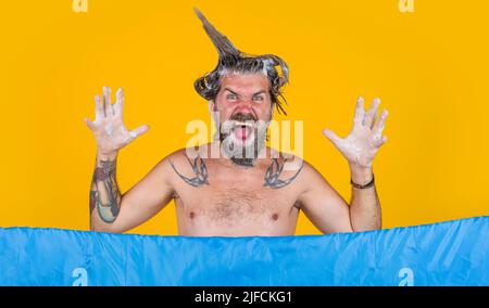 Uomo divertente con schiuma sulla testa facendo la doccia. Ragazzo bearded che lava in bagno. Foto Stock