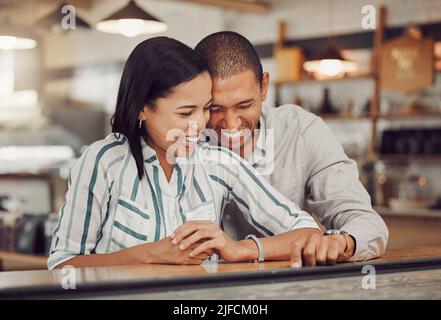 Amorevole coppia di gara mista ridendo e godendo il tempo insieme il primo giorno. Giovane donna e uomo in una data caffè in un caffè Foto Stock
