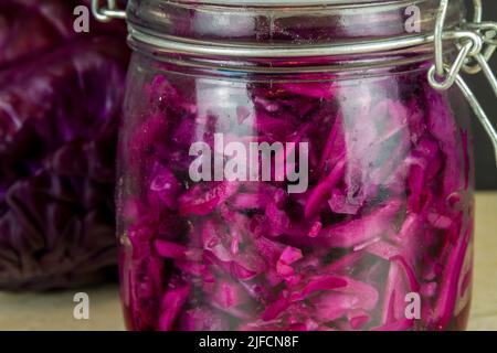Vaso di crauti appena fatti con cavolo rosso intero dietro primo piano, macro. Foto Stock