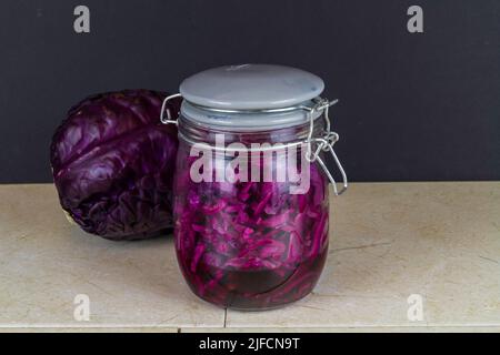 Vaso di crauti appena fatti con cavolo rosso intero dietro, paesaggio. Foto Stock