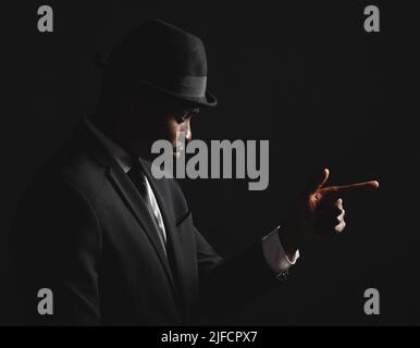 Dapper e giovane uomo fiducioso vestito in abito formale su sfondo scuro. Bell'uomo afroamericano che guarda elegante e sofisticato Foto Stock