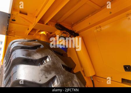 Enormi ruote posteriori del dumper a cassone ribaltabile con angolazione insolita in primo piano. Le ruote sono dotate di un battistrada per il movimento del dumper su terreni sfusi. Foto Stock