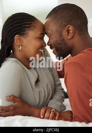 Primo piano di una amorevole coppia afroamericana che tocca la fronte mentre si trova insieme su un letto. Felice giovane uomo e donna che condividono romantico intimo Foto Stock