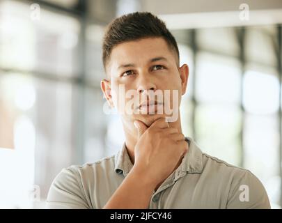 Premuroso uomo d'affari giovane di razza mista con mano sul progetto di pianificazione del mento, riflettendo le idee. Pensivo pensiero professionale sul futuro mentre Foto Stock