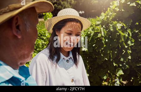 Sorridente coppia gara mista legame sul vigneto. Felice marito e moglie ispanica ridendo e godendo la giornata in una fattoria dopo la degustazione di vino durante un fine settimana Foto Stock