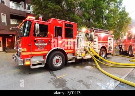 Seattle - 30 giugno 2022; i motori antincendio della città di Seattle che lavorano un incendio attivo a Seattle con tubi gialli pieni attaccati all'apparecchio rosso Foto Stock