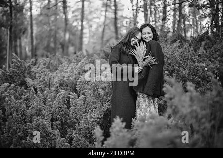 Ritratto bianco e nero di due giovani donne vestite d'epoca che camminano nel parco autunnale Foto Stock