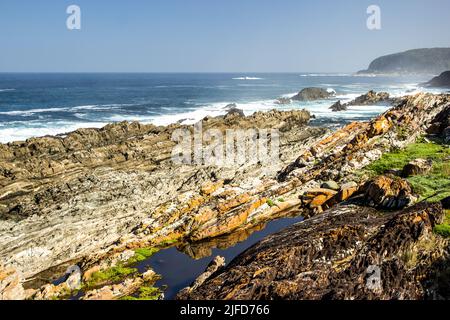 Guardando lungo l'aspra e frastagliata costa rocciosa della sezione Tsitsikamma del Parco Nazionale Garden Route, del Sudafrica Foto Stock