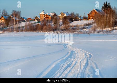 Tracce di veicoli e persone sul fiume Volga ghiacciato e innevato Foto Stock