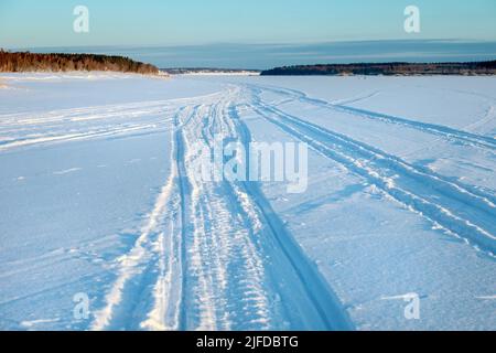 Tracce di veicoli e persone sul fiume Volga ghiacciato e innevato Foto Stock