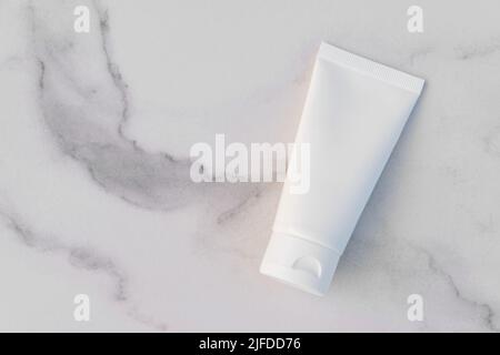 Tubo per bottiglia in crema cosmetica senza marchio bianco strizzarlo su sfondo di marmo. Cosmetici naturali di spa di tipo oranico. Mockup, modello, vista dall'alto Foto Stock