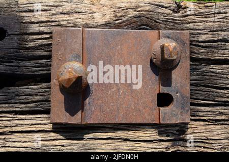 Una vecchia ferrovia abbandonata con un bullone arrugginito su una vecchia ferrovia spaccata traversina, vista dall'alto. Foto Stock