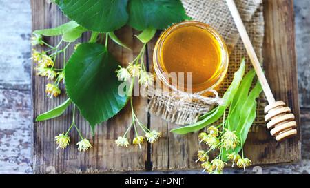 Miele di Linden in un vaso. Foglie e fiori di tiglio. Miele di tiglio fresco. Foto Stock