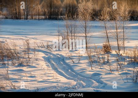 Tracce di veicoli e persone sul fiume Volga ghiacciato e innevato Foto Stock