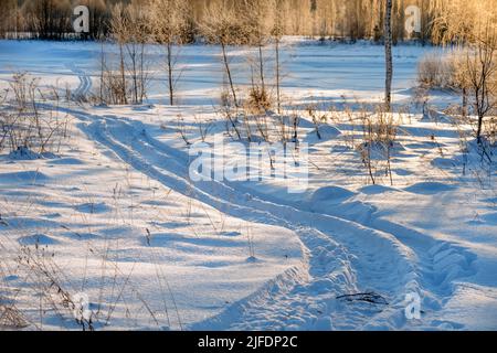 Tracce di veicoli e persone sul fiume Volga ghiacciato e innevato Foto Stock