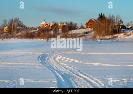 Tracce di veicoli e persone sul fiume Volga ghiacciato e innevato Foto Stock