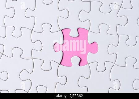 Pezzo di puzzle su carta rosa. Disposizione piatta, direttamente sopra. Spazio di copia. Foto Stock
