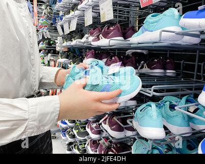 Mosca, Russia, marzo 2022: Qualcuno sceglie sneakers blu per bambini o donne nel negozio di articoli sportivi Decathlon. Foto Stock