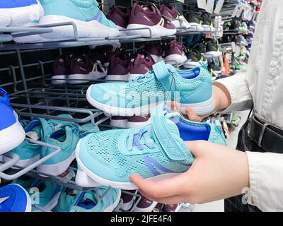 Mosca, Russia, marzo 2022: Qualcuno sceglie sneakers blu per bambini o donne nel negozio di articoli sportivi Decathlon. Foto Stock