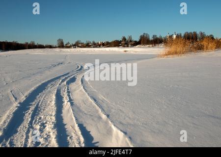 Tracce di veicoli e persone sul fiume Volga ghiacciato e innevato Foto Stock