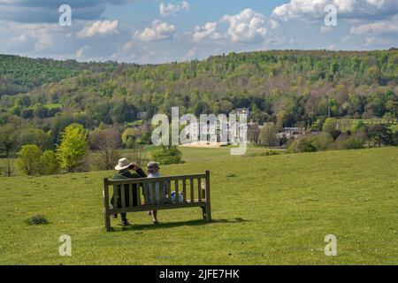 Due persone seduti su una panchina e ammirando la vista dal South Downs guardando verso il basso sul West Dean College Foto Stock
