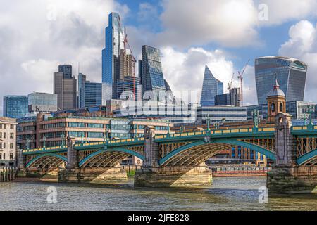 Il colorato Southwark Bridge attraversa il Tamigi a Londra con Canary Wharf alle spalle Foto Stock