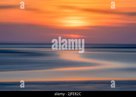 Il sole che tramonta sulla spiaggia di West Wittering lascia la spiaggia sabbiosa bagnata di luce esotica. Foto Stock