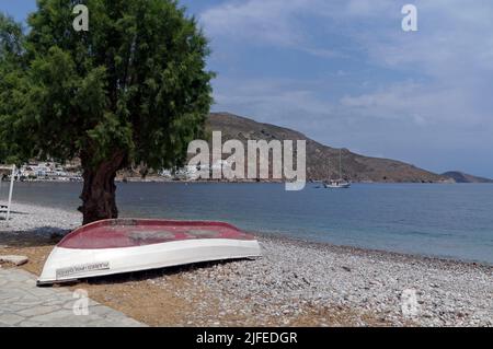 Una barca da pesca greca rovesciata sotto un albero di tamerico. Marco Polo, Spiaggia, Livadia Village, Tilos Island, Dodcaneso, Grecia Foto Stock
