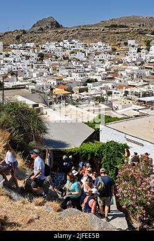 Lindos, Rodi, Grecia - Maggio 2022: I visitatori salendo i gradini per raggiungere l'antica acropoli della città Foto Stock