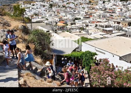 Lindos, Rodi, Grecia - Maggio 2022: I visitatori salendo i gradini per raggiungere l'antica acropoli della città Foto Stock